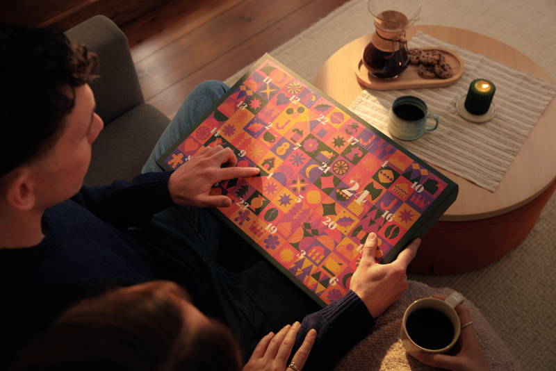 Person zeigt auf das erste Türchen eines Adventskalender, auf dem Tisch steht eine Chemex und eine Tasse.