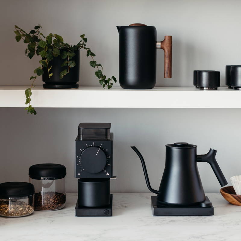 Fellow Stagg EKG Pro kettle is standing on a  shelf next to Ode Grinder. On top you can see the Fellow Clara French Press.
