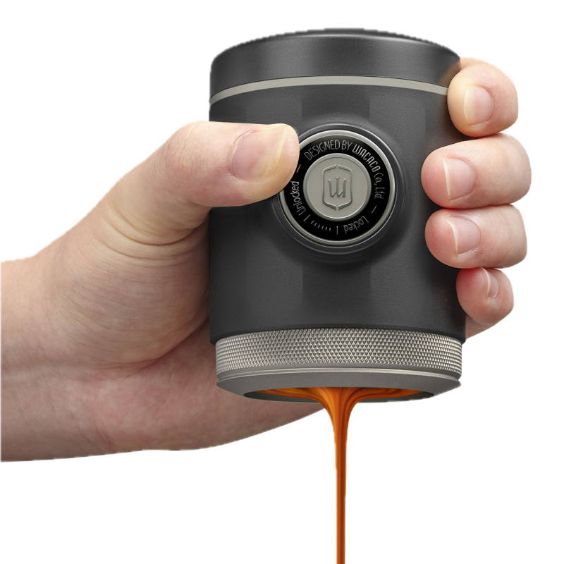 Wacaco Picopresso wird in einer Hand gehalten. Es fließt ein dunkler Espresso aus dem Wacaco Picopresso.
