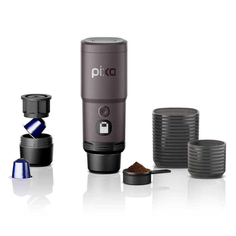 Eine tragbare Espresso-Kaffeemaschine der Marke "pixa" in Dunkelbraun, umgeben von ihrem Zubehör. Das Gerät zeigt ein leuchtendes Schlosssymbol auf einem kleinen Display. Links daneben ist ein geöffneter Kapseladapter mit blauen Kaffeekapseln zu sehen. Vorne liegt ein Messlöffel mit Kaffeepulver, und rechts stehen zwei anthrazitfarbene Becher mit horizontalem Rillenmuster.