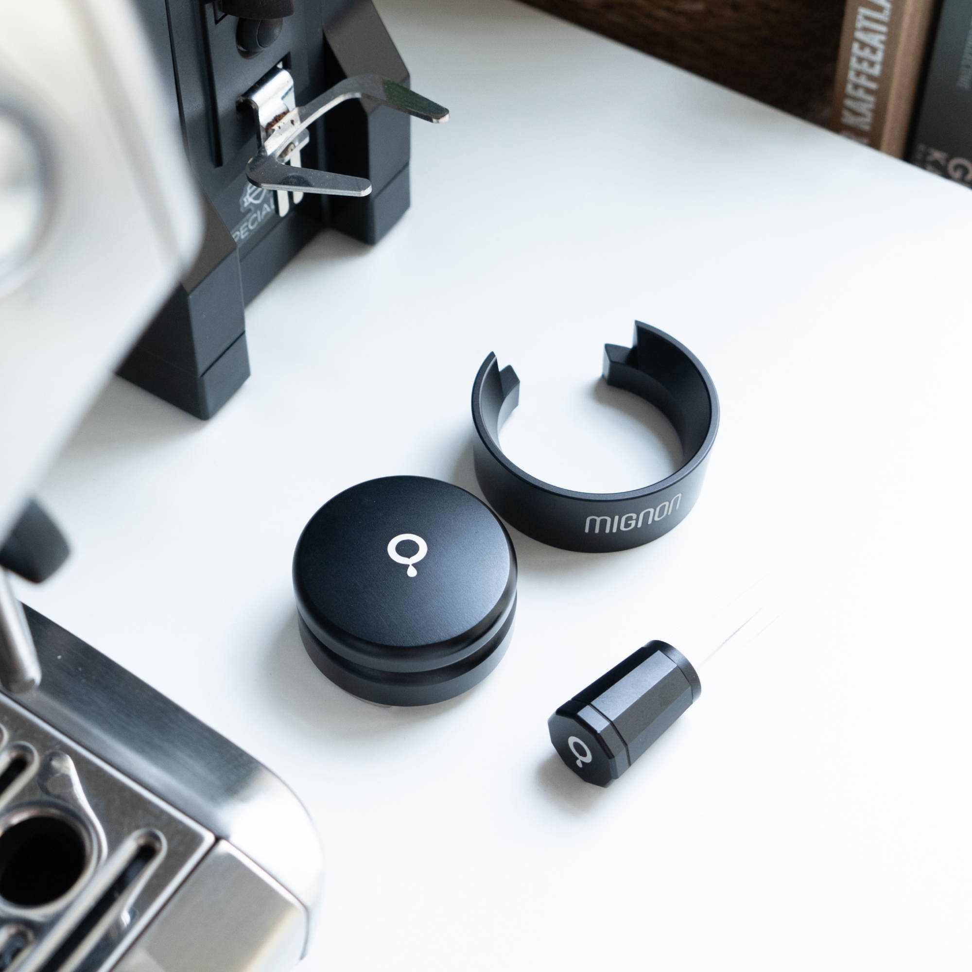 The Coffee Circle Leveler, WDT tool, and Eureka Dosing Funnel lie on a white table. Behind them, a Eureka Specialità can be seen.