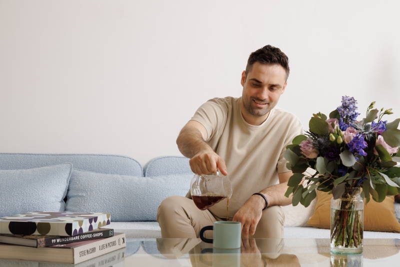Mann schenkt sich einen Kaffee auf der Couch mit dem Hario V60 Range Server ein