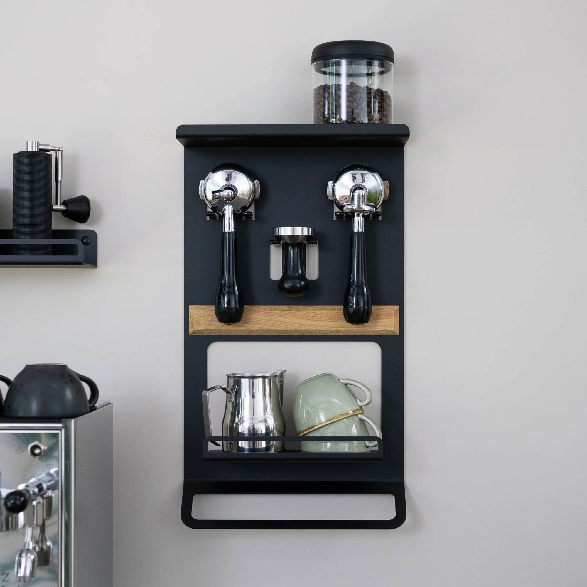 Flate Barista Rack hängt an der Wand befüllt mit zwei Siebträgern, einem Tamper, einem Milchkännchen und Tassen.