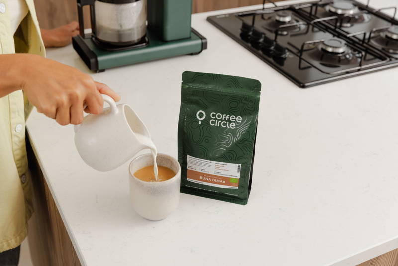 Einschenken von Milch in den fertigen Buna Dimaa aus dem Moccamaster