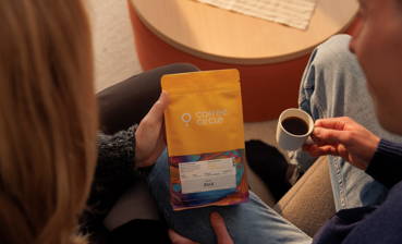 Paar auf der Couch hält eine Packung Guji Espresso in den Händen.
