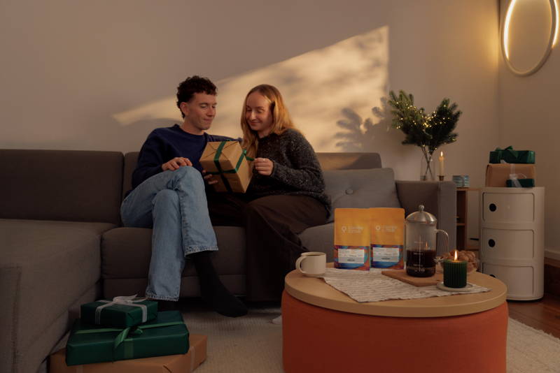 Mann und Frau packen auf der Couch ein Geschenk aus, im Vordergrund steht das Holiday Roast Set 2025