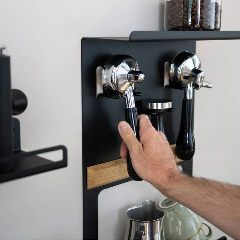 Flate Barista Rack hängt an der Wand befüllt mit zwei Siebträgern, einem Tamper, einem Milchkännchen und Tassen.