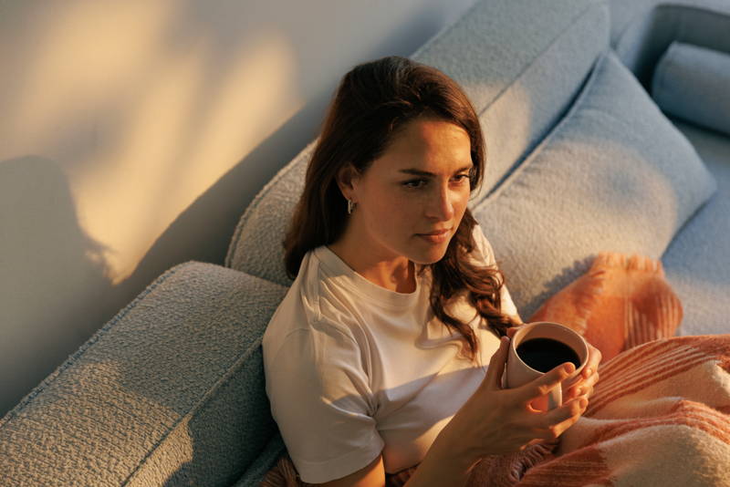 Woman sitting on a sofa, holding a cup of coffee