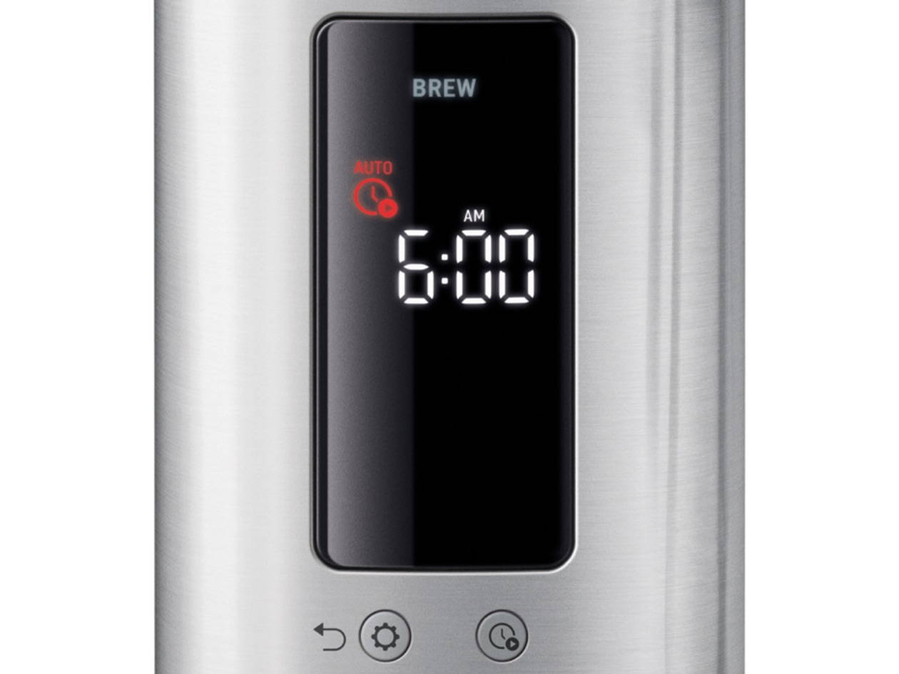 Eine Nahaufnahme des Bedienfelds einer Sage Kaffeemaschine mit gebürsteter Edelstahloberfläche. Ein rechteckiges digitales Display zeigt oben das Wort "BREW". Darunter ist ein rotes "AUTO"-Symbol mit einer Uhr zu sehen, gefolgt von der Uhrzeit "6:00 AM". Unter dem Display befinden sich drei runde Berührungstasten: "Abbrechen", "Einstellungen" und "Auto-Start".