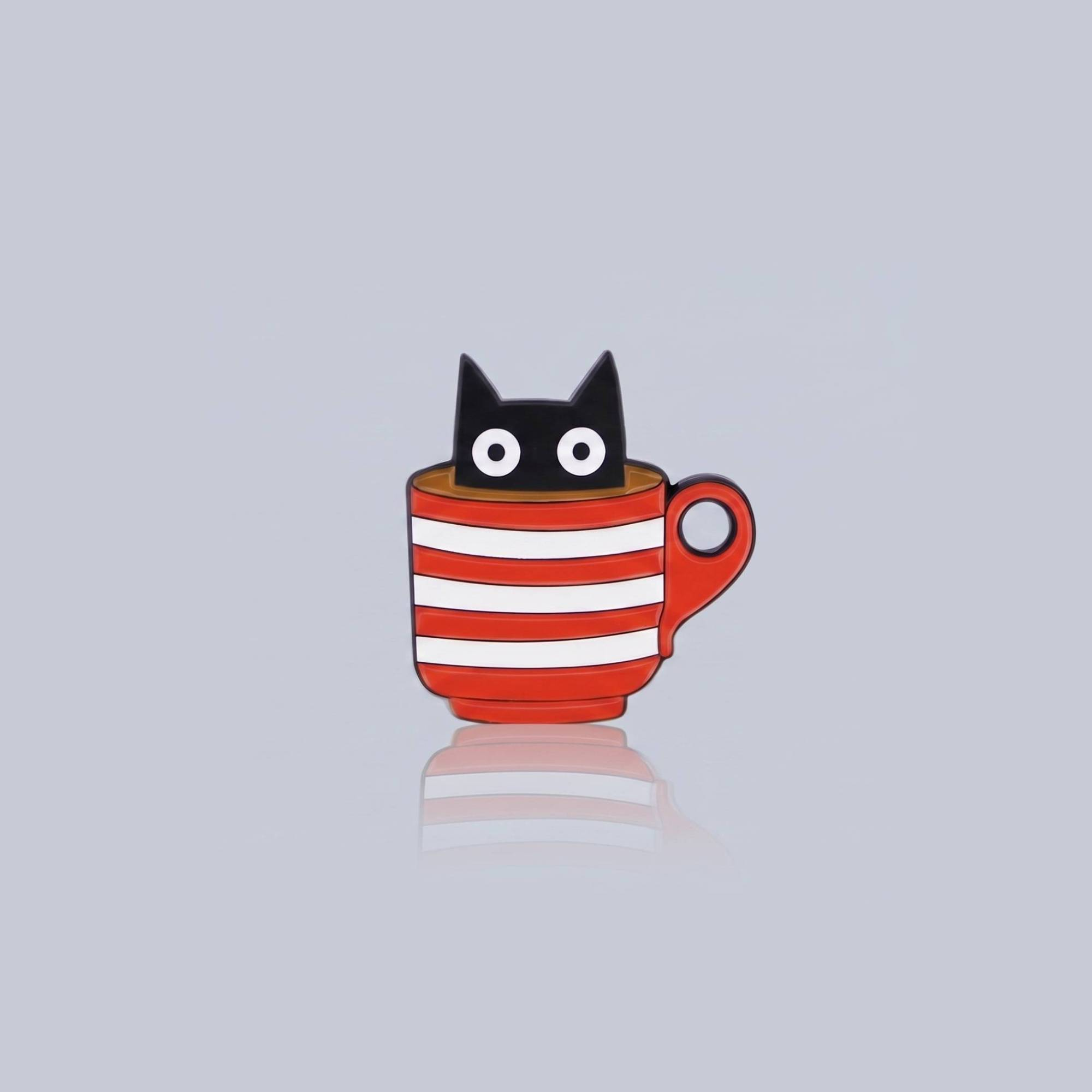 Ein Emaille-Pin, der eine schwarze Katze mit großen weißen Augen zeigt, die aus einer rot-weiß quergestreiften Kaffeetasse herausschaut.