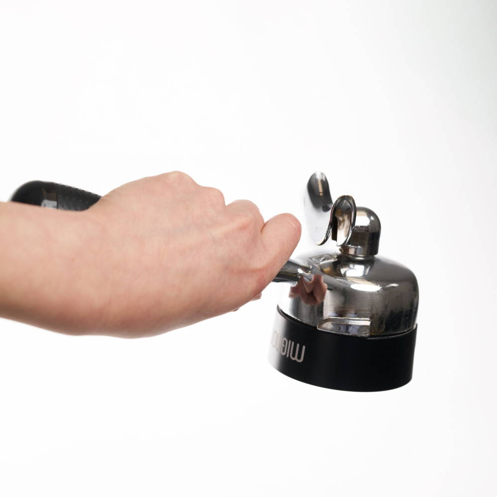 A hand holds a portafilter with the magnetically attached doing funnel.