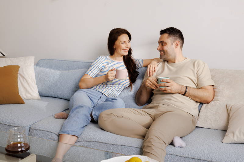 Mann und Frau sitzen auf der Couch mit einem Kaffee in der Hand