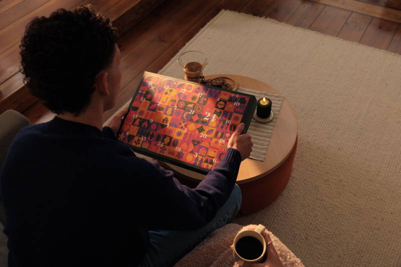 Mann hält Adventskalender 2025 in der Hand