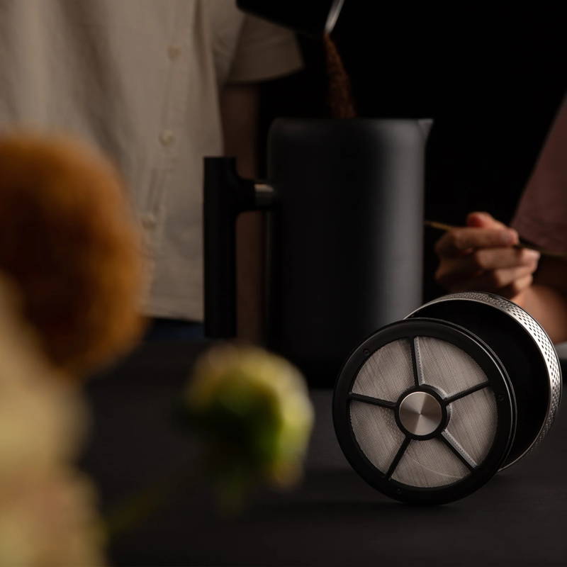 Fellow Clara French Press steht auf einem Tisch.Der obere Teil der French Press liegt neben der Kanne.