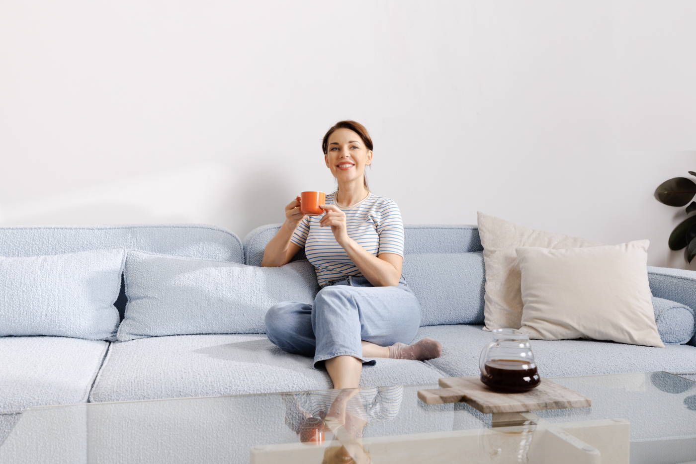Frau sitzt auf der Couch mit einem Kaffee in der Hand, auf dem Tisch steht ein Hario V60 Range Server