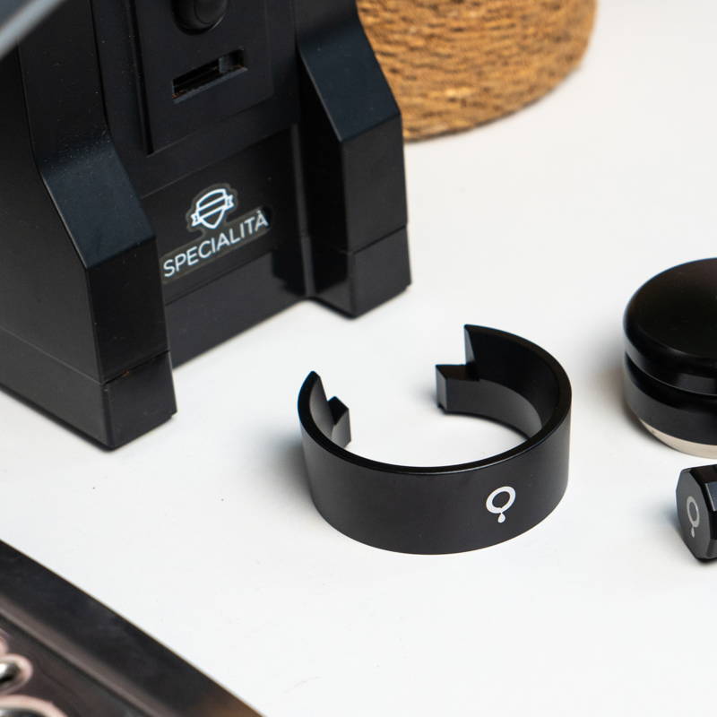 Coffee Circle Dosing Funnel ist auf einem weißen Hintergrund zu sehen. Dahinter steht eine Eureka Specialità Mühle.