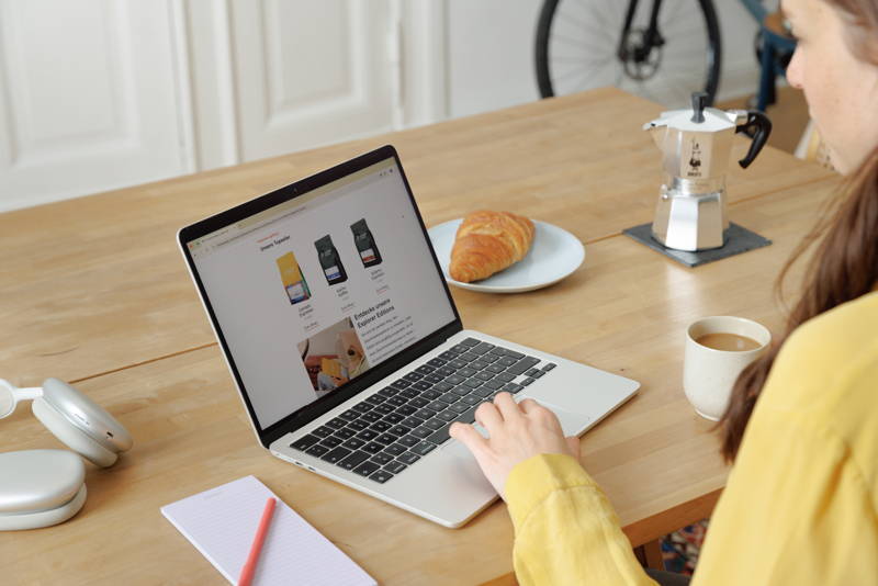 Frau sitzt mit Laptop am Tisch und liest Coffee Circle Newsletter