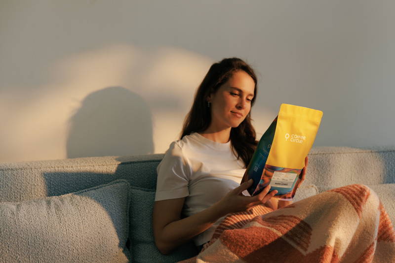 Frau schaut sich einen Bag Maíra Gomez Filterkaffee auf der Couch an