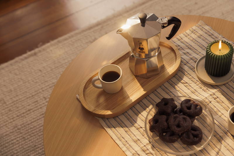 Eine gefüllte Espressotasse steht neben einer Bialetti Herdkanne.