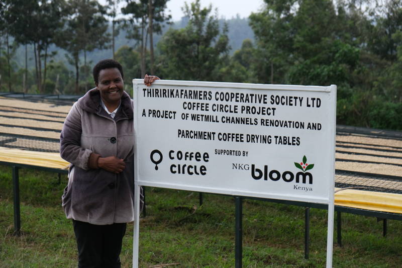 Frau lehnt an Thiririka farmers Cooperative Society Shild