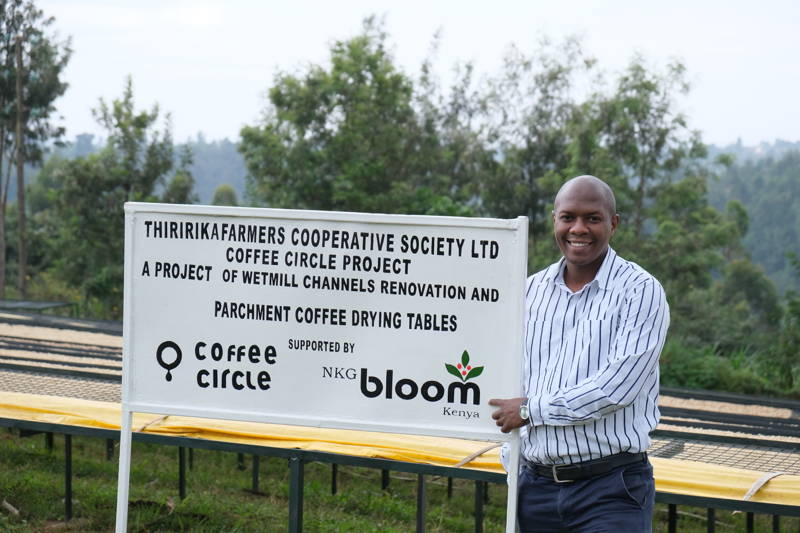 Mann steht neben Thiririka farmers Cooperative Society Shild