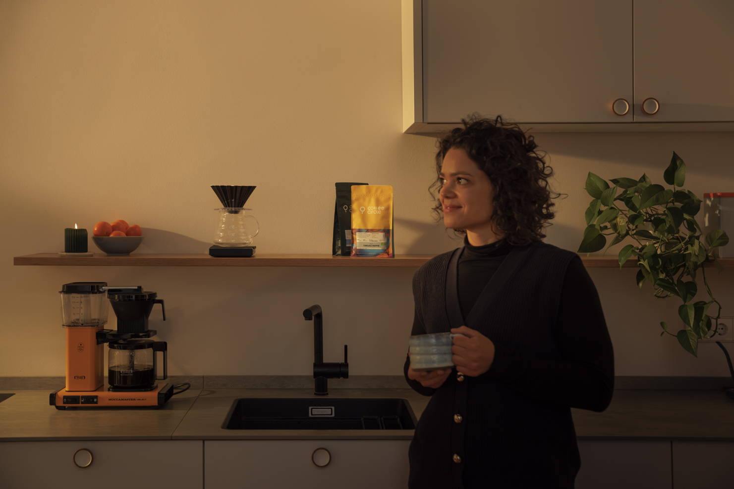 Eine Frau steht in der Küche und trinkt Kaffee.
