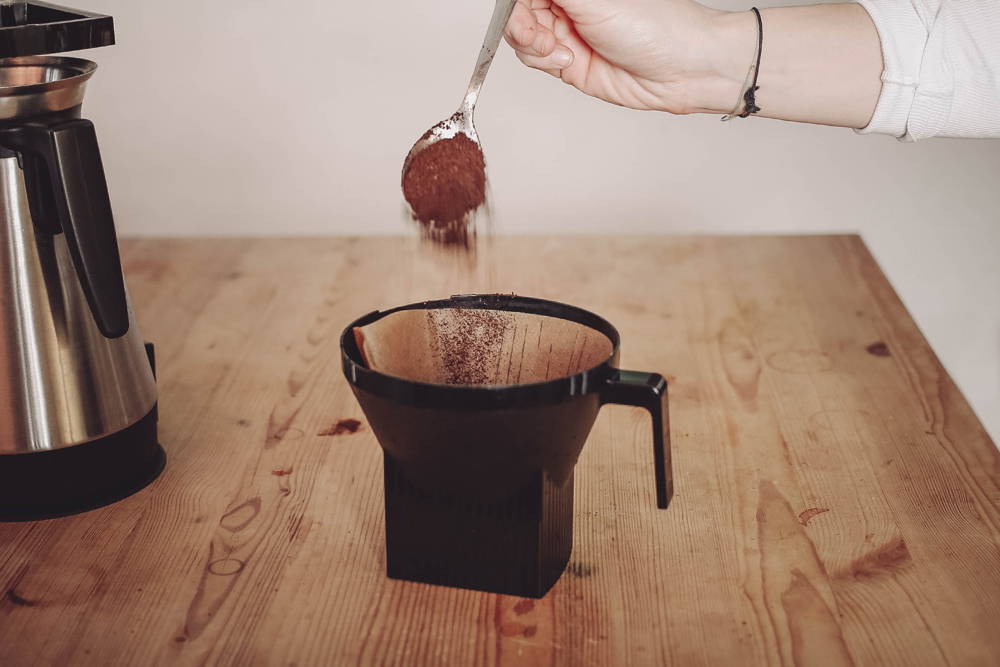 Füge nun 8 Esslöffel Kaffeemehl in den Kaffeefilter hinzu.