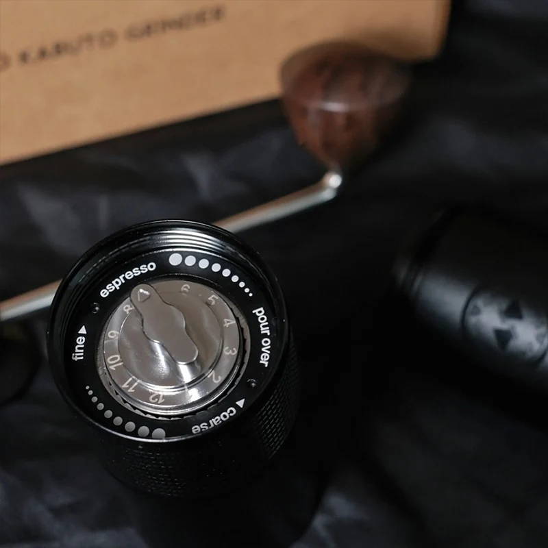 Nahaufnahme der Unterseite der HARIO Kabuto Mühle mit dem metallenen Mahlgrad-Einstellrad, umgeben von weißen Beschriftungen für "espresso" und "pour over" sowie Richtungspfeilen für fein und grob.